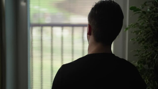 Man silhouette watching through window stretch arms behind the head 4K