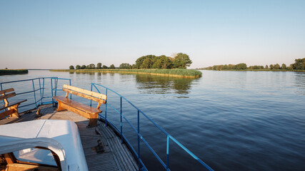 Naklejka premium View from the front deck of the ship to a branching river on a quiet summer evening.