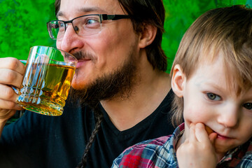 morning family happiness concept. Father and son are drinking tea in the kitchen, painted like a forest. dad and son are having fun.