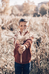 Portrait of happy teenager boy in field of pampas grass. Slow life in countryside. Joyful child...