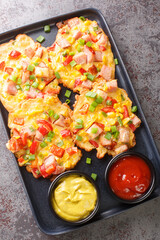 Vegetable pancakes with ham served with sauce close-up on a plate on the table. Vertical top view from above