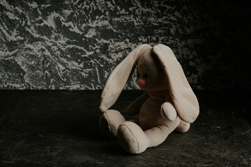 Fototapeta na wymiar Plush toy is sitting in the dark room. Child abuse and punishment concept. Lonely concept, international missing children's day