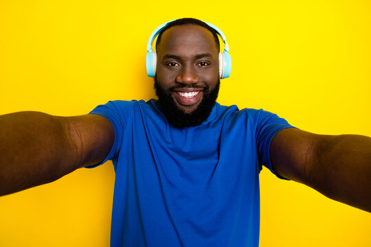 Self-portrait of attractive cheerful guy listening song rest weekend free time isolated over bright yellow color background