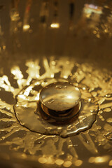 Expensive shining golden wet sink with water drops, a detail of a rich luxury interior, top view
