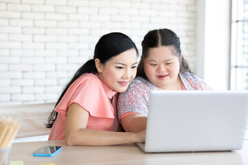 down syndrome teenage girl and her teacher using laptop computer together on a table