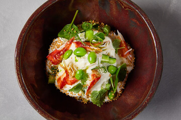 Chef salad with crab, quinoa, vegetables and edamame beans on dark homemade ceramic bowl. Salad bowl with crab, avocado, cream sauce in modern serveware. Modern dishware on concrete background.