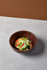 Chef salad with crab, quinoa, vegetables and edamame beans on dark homemade ceramic bowl. Salad bowl with crab, avocado, cream sauce in modern serveware. Modern dishware on concrete background.
