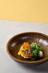 Pumpkin steak with chicken and spinach on dark ceramic plate. Healthy food in modern dishware. Innovative recipes in contemporary style. Roasted turkey with pumpkin on gray concrete background.