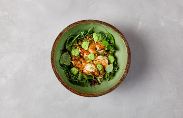 Green bowl with prawns, quinoa and avocado cream on handmade ceramic plate. Salad with shrimp in dark modern dishware. Healthy food in contemporary style