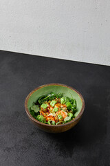 Green bowl with prawns, quinoa and avocado cream on handmade ceramic plate. Salad with shrimp in dark modern dishware. Healthy food in contemporary style