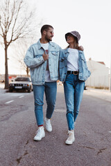 Stylish vintage young couple walking on the road looking each other with denim clothes
