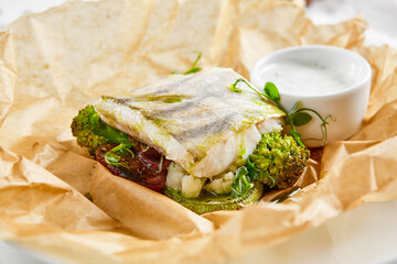 White fish fillet with broccoli in rustic style. Healthy eating: cooked fish fillet with vegetables garnish. Diet food with whitefish and broccoli. Steam vegetables with roasted zander fillet.