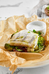 White fish fillet with broccoli in rustic style. Healthy eating: cooked fish fillet with vegetables garnish. Diet food with whitefish and broccoli. Steam vegetables with roasted zander fillet.