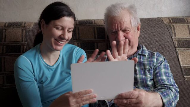 Woman And Elderly Man Communicate Video Call Over Internet Greeting Waving Hand