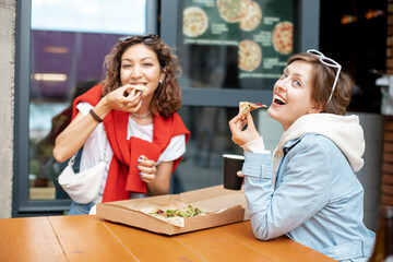 Happy girls chat and relax and eat fast food pizza. Communication and relationship