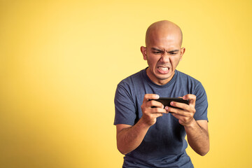 excited young asian man playing video game on his smartphone