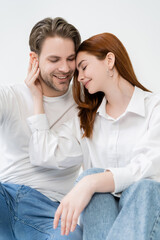 Young woman in shirt touching smiling boyfriend isolated on white.