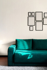 Part of interior with bright green sofa and empty photo frames.