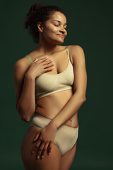 Portrait of young tender woman posing in comfortable cotton underwear isolated over green studio background