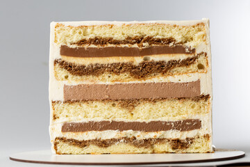 On a white background, a sweet pastry cake is cut in half, the cake is cut in half, the filling and biscuits are visible.Catalog demonstration.