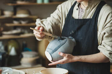 Female artisan business, potter making ceramic vase for sale in handmade store