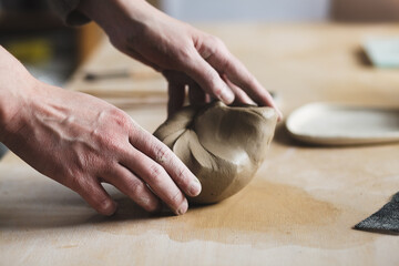 Obraz na płótnie Canvas Potter shaping natural raw clay, pottery studio background