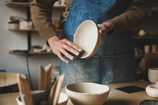 Pottery making studio workshop, hands making ceramic bowl ready for further roasting 