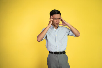 Stressed asian young businessman holding his head over isolated background