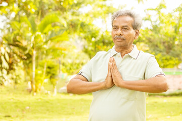 Naklejka na ściany i meble Senior man in namaste pose while doing yoga with copy space - concept of fitness, active healthy lifestyle and morning routine.