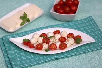 Mozzarellakugeln mit Tomaten auf einem Teller.