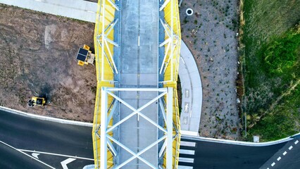 top down drone shot of a yellow and white footbridge