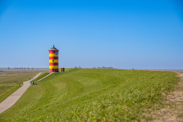 Fototapeta na wymiar The yellow red lighthouse of Pilsum on a sunny day