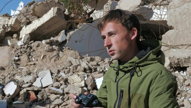Photographer takes photos in trouble spot. Military correspondent reporting on current activities in conflict-affected area. Cameraman, journalist shooting in ruins after hostilities in war zone