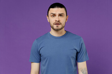 Obraz premium Young disappointed sad displeased depressed man 20s wearing basic blue t-shirt with blank print design look camera isolated on plain purple color background studio portrait. People lifestyle concept.