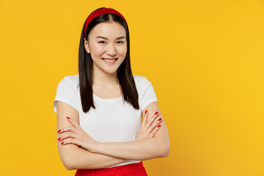 Amazing magnificent fun young girl woman of Asian ethnicity 20s years old wears white t-shirt hold hands crossed isolated on plain yellow background studio portrait. People emotions lifestyle concept.