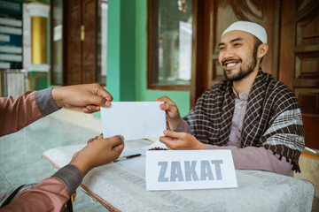 portrait of happy muslim man paying zakat for eid mubarak at the mosque