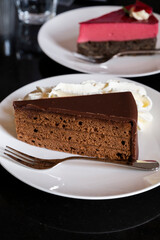 Piece of famous Sachertorte chocolate cake with apricot jam  and Poppy seed cake with raspberry mousse of Austrian origin served with whipped cream