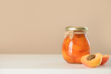 Homemade Apricot jam in glass jar on beige background. Summer harvest and canned food