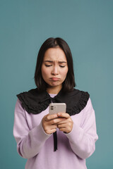 Fototapeta premium Young asian woman frowning and using mobile phone