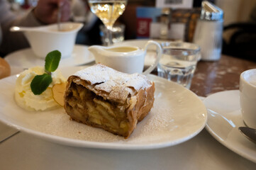 Austrian sweet dessert, portion of apple strudel with whippen cream and hot vanilla sauce served in old bakery cafe in Vienna, Austria