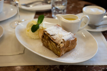 Austrian sweet dessert, portion of apple strudel with whippen cream and hot vanilla sauce served in old bakery cafe in Vienna, Austria