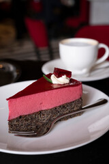 Piece of famous Poppy seed cake with raspberry mousse of Austrian origin served with whipped cream and cup of coffee