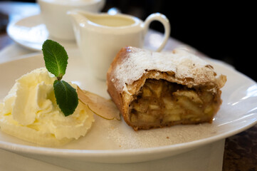 Austrian sweet dessert, portion of apple strudel with whippen cream and hot vanilla sauce served in old bakery cafe in Vienna, Austria