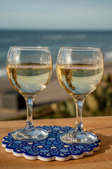 Glasses of Spanish dry white wine served on andalusian style board with blue ornament on beach terrace with view on Mediterranean sea
