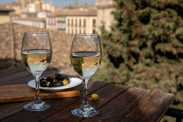 Two glasses of Spanish dry rueda white wine served with olives on roof terrace with view on old part of Andalusian town Granada, Spain