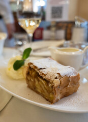 Fototapeta na wymiar Austrian sweet dessert, portion of apple strudel with whippen cream and hot vanilla sauce served in old bakery cafe in Vienna, Austria