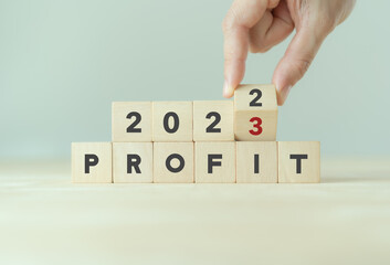 Business profit plan concept in 2023 . Build a profit and financial plan. Hand flip wooden cubes...