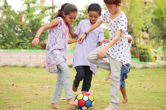 group of multiethnic diverse kids playing football at park - concept of summer vacation, holidays, active childhood lifestyle