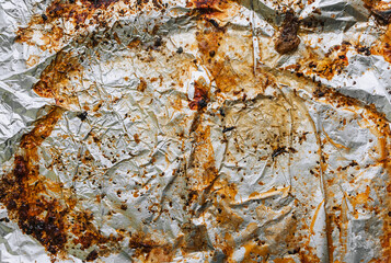 Background, texture, top view of dirty, greased, after cooking a meat dish, crumpled foil. Photograph of food preparation.