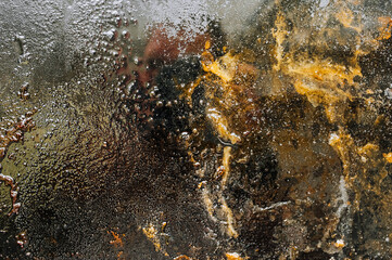 Texture, background, top view of a black tray smeared in fat, oil, pieces of meat, after cooking the dish. Photography, abstraction.